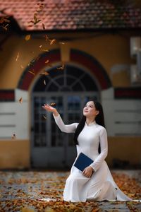 Elegant Vietnamese student in white Ao Dai reading, timeless beauty amidst classic architecture.-7