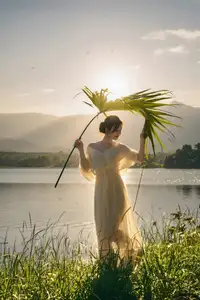 Golden Hour Serenity: Woman in White Dress Embracing Nature's Beauty by the Lake at Sunset.-4