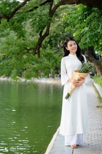Elegant Vietnamese girl in traditional white Ao Dai by the lake, embodying cultural beauty-5