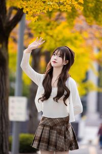 Young Asian Girl in Plaid Skirt Embracing Autumn Foliage-1