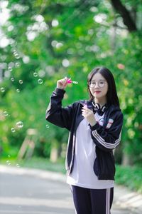 Radiant Youth: Girl in Uniform Playfully Blowing Bubbles in Lush Greenery 1000019736-5