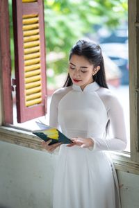 Graceful Vietnamese Girl in White Ao Dai by Window, Celebrating Traditional Beauty-2
