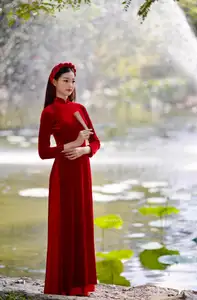 Discover the enchanting beauty of a Vietnamese woman in a traditional Red Ao Dai by the tranquil water.-3